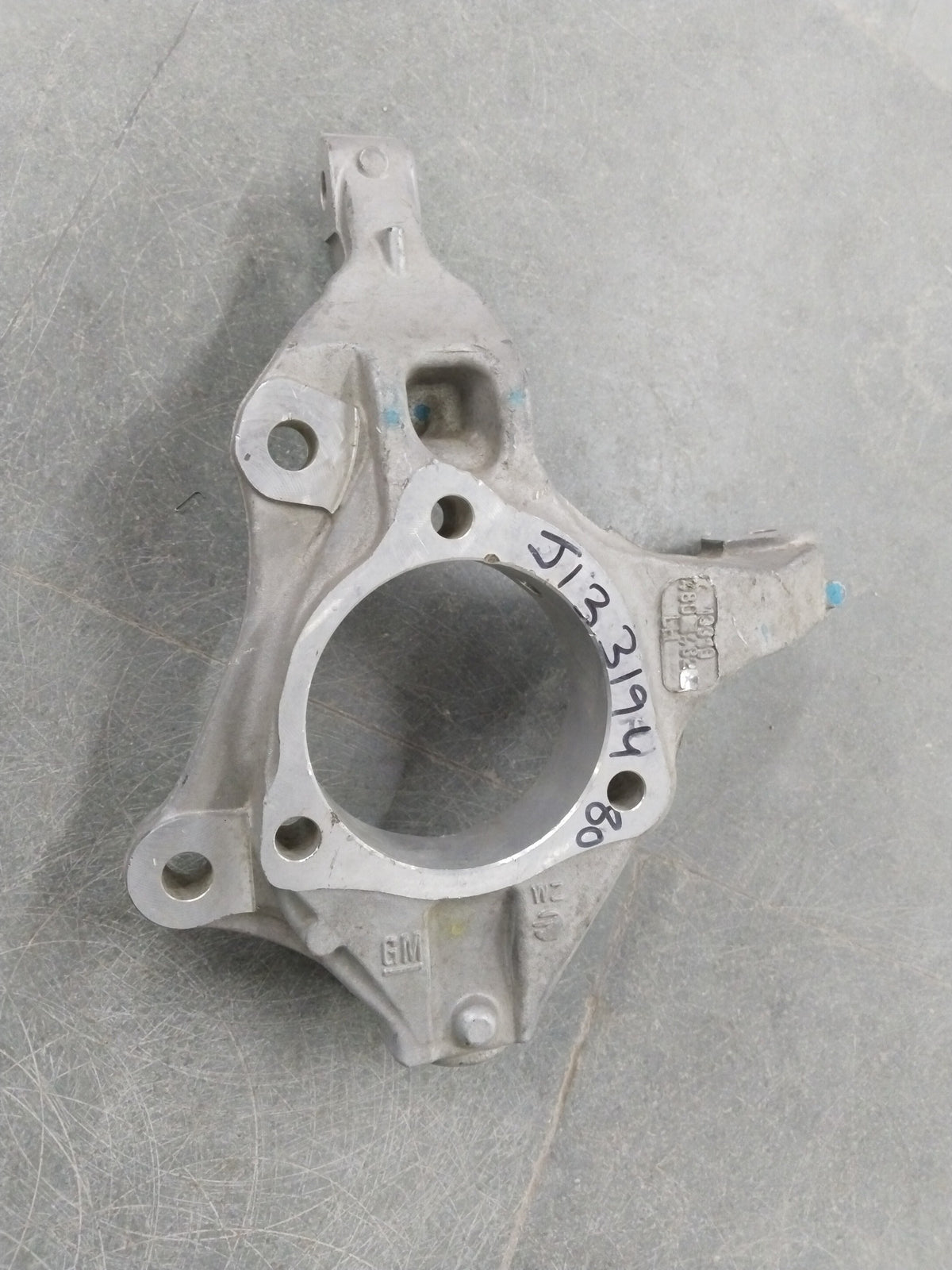 General Motors Chevrolet Cruze steering knuckle, metallic component with bolt holes, designed for vehicle suspension and steering system.