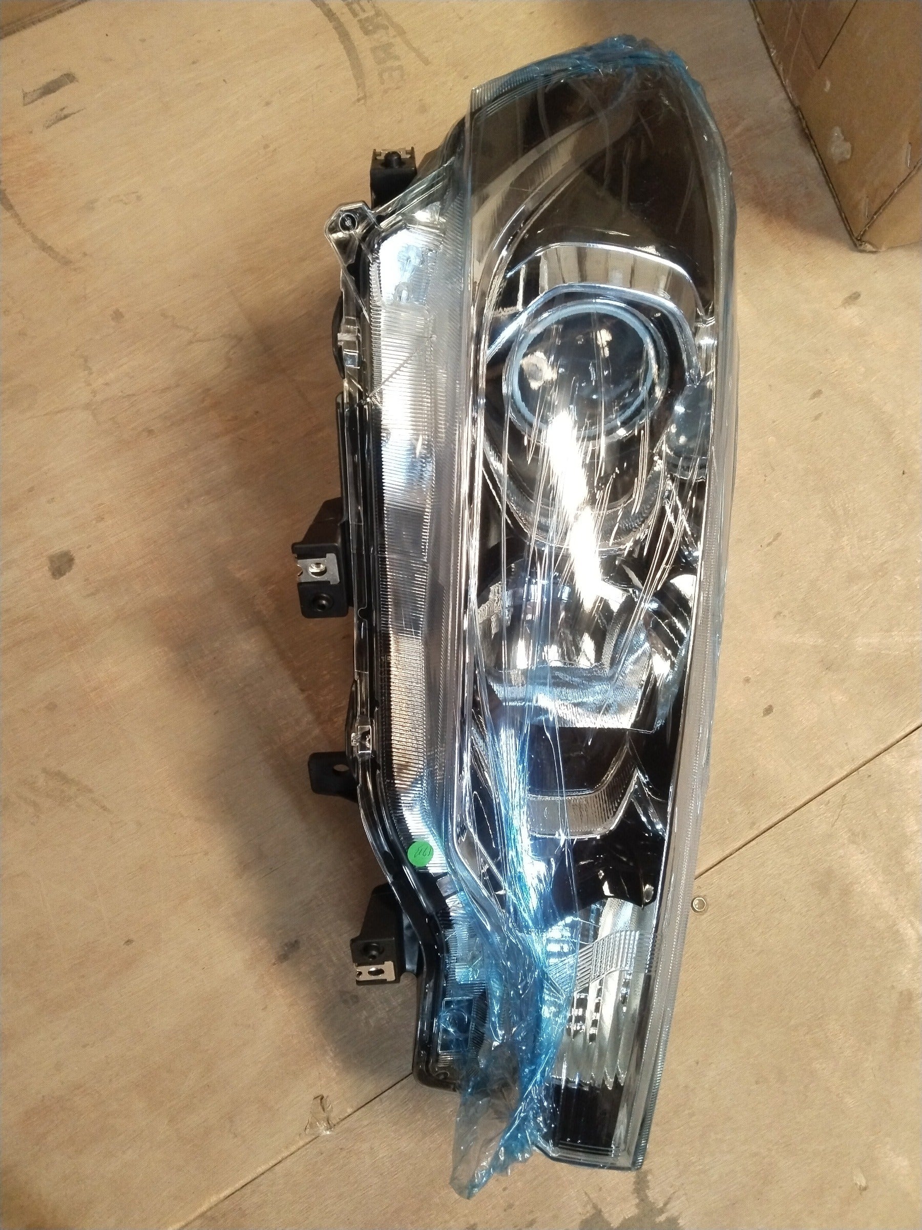 Maruti Suzuki head lamp for Ertiga, right side, clear view of the automotive headlight assembly with reflective surfaces and mounting details.