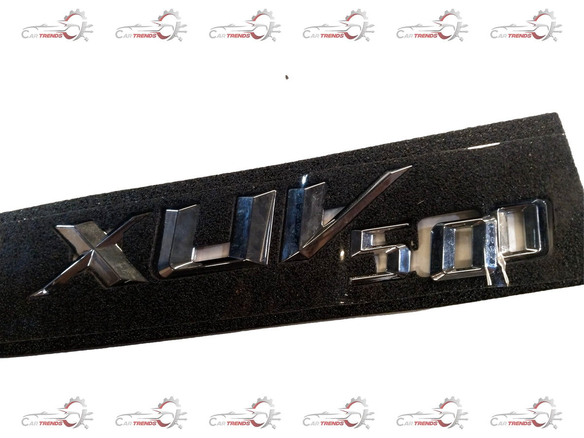 Mahindra badge for XUV500 tailgate, featuring the Mahindra logo and product code #0108FAW00150N, mounted on vehicle tailgate