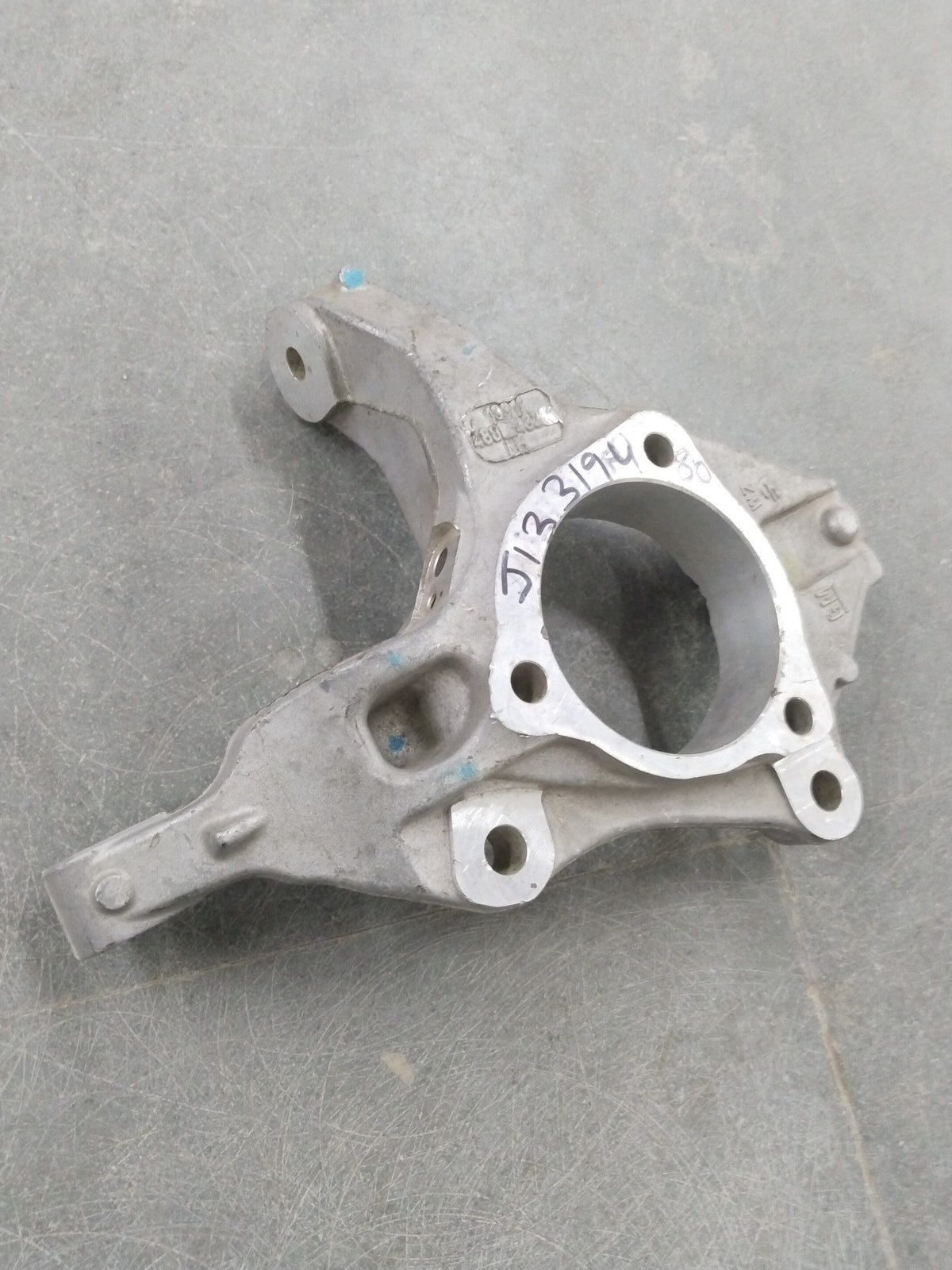 Chevrolet Cruze steering knuckle by General Motors, showing the metal component with mounting points and bolt holes.