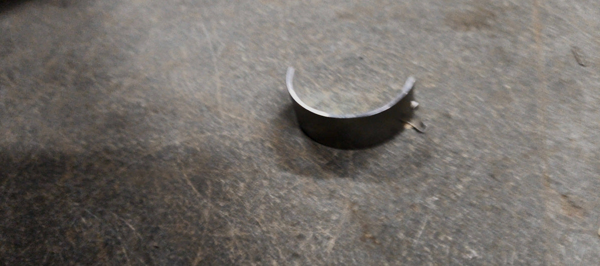 Maruti Suzuki lower crankshaft bearing for Swift, Baleno, Brezza, and Ertiga models, showing the metal bearing component.