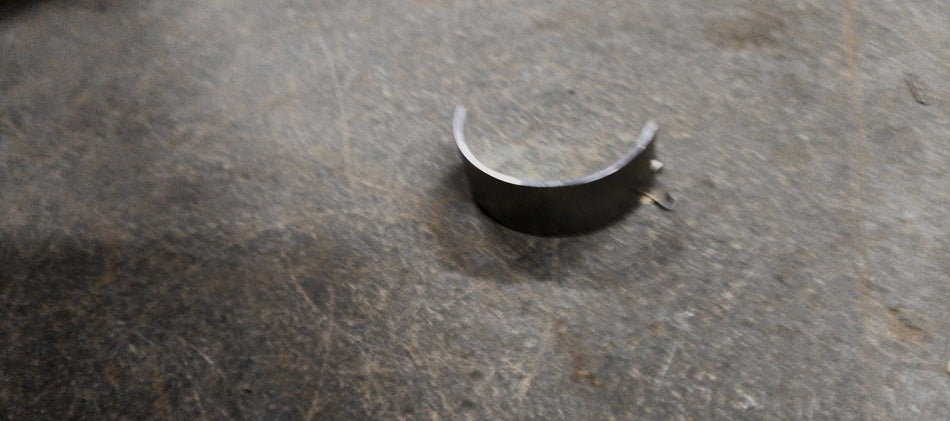 Maruti Suzuki lower crankshaft bearing for Swift, Baleno, Brezza, and Ertiga models, showing the metal bearing component.