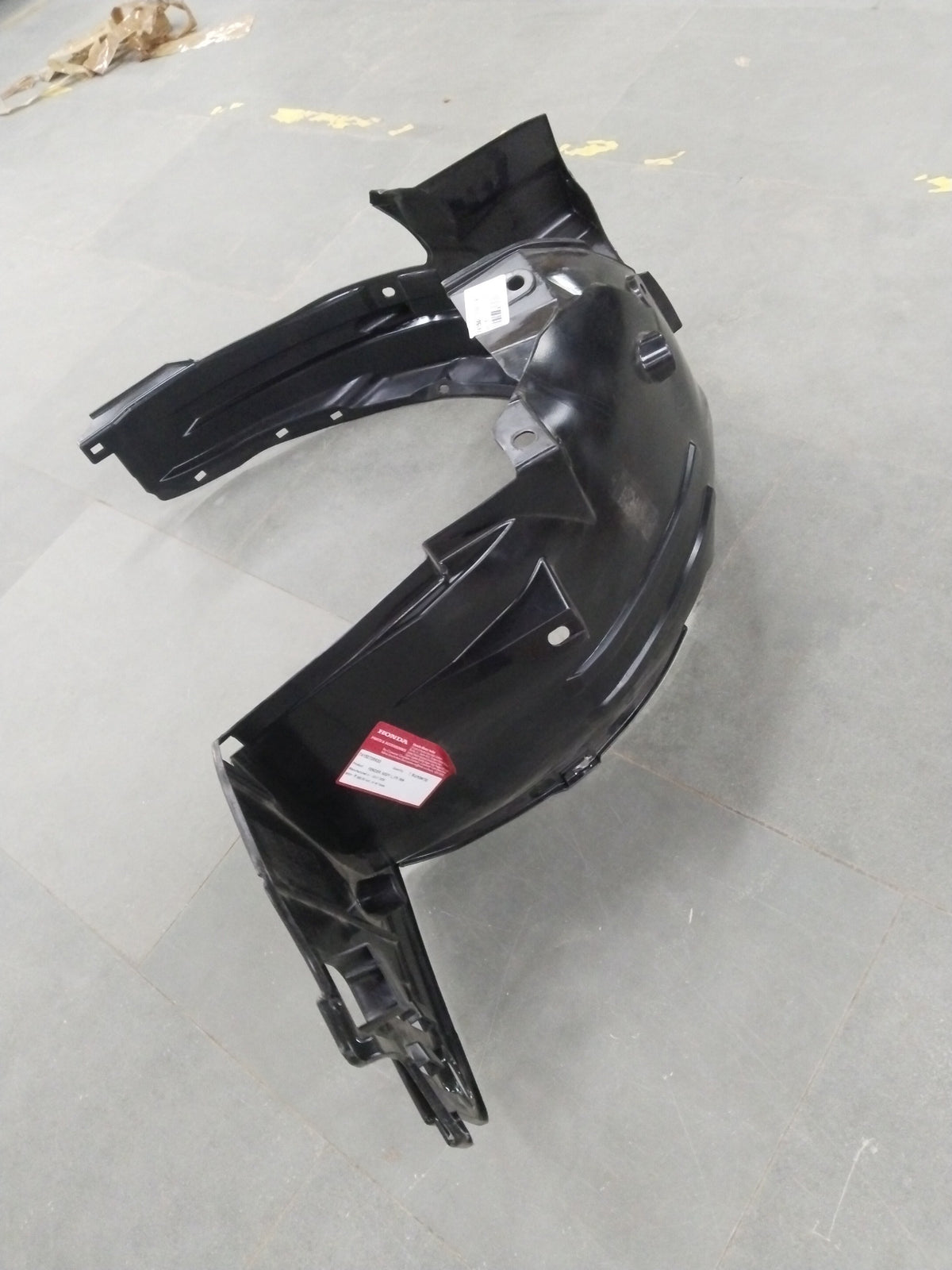 Honda Brio front inner left fender assembly in black with mounting points and surface details.