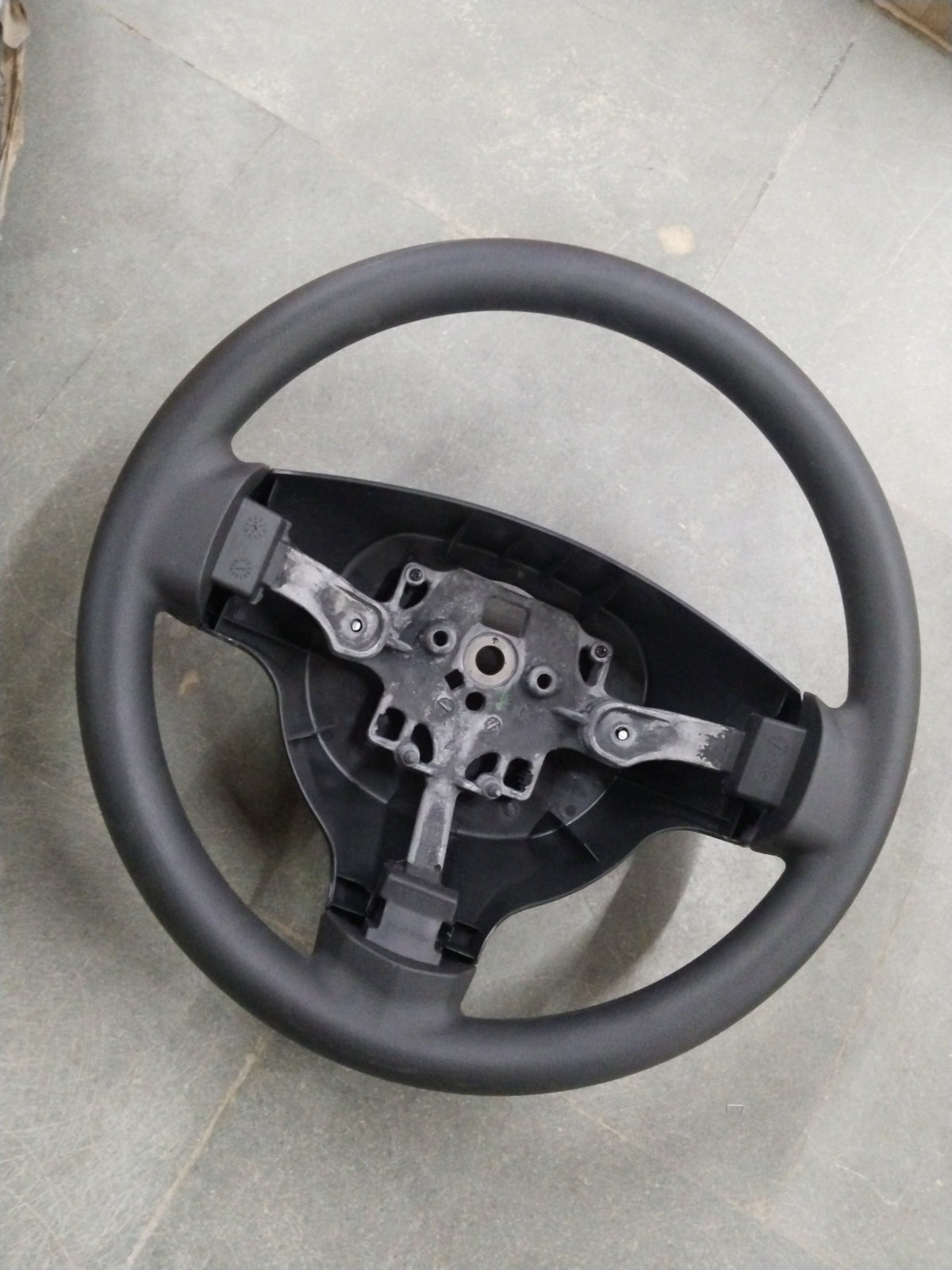 General Motors Chevrolet Enjoy steering wheel assembly, showing the black wheel and mounting components in a detailed image.