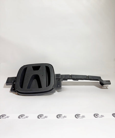 Honda grille emblem attached to the front of a vehicle, featuring the Honda logo on a metallic base with model-specific design.