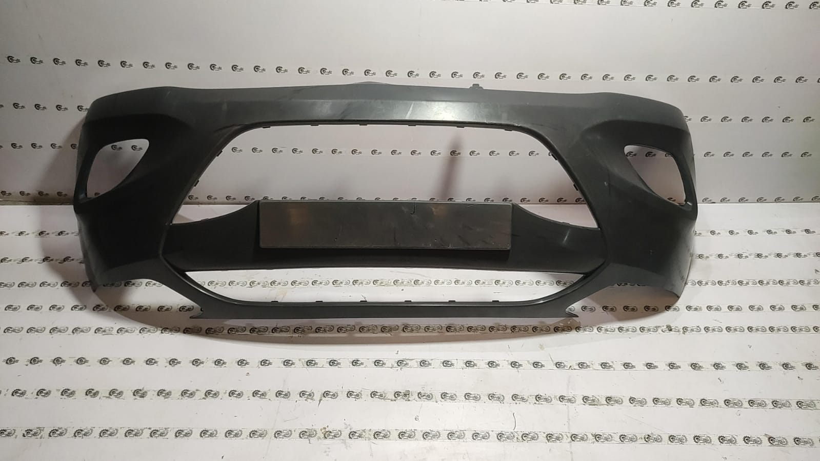 Front bumper for Hyundai I10 by CarTrends, showing a black plastic exterior with mounting points and a smooth finish.