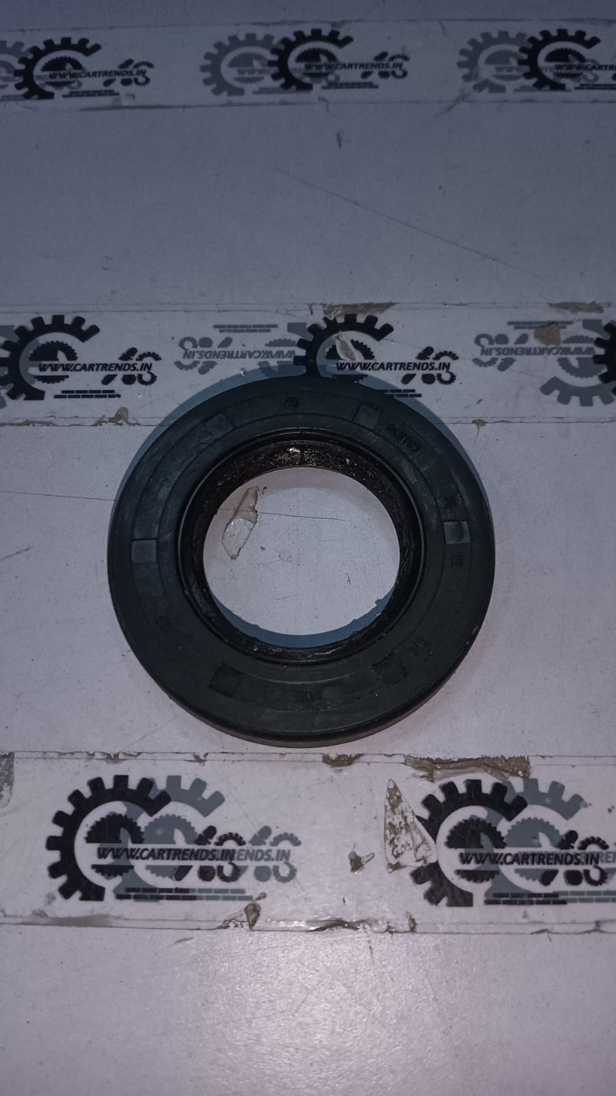 Front oil seal for Chevrolet Aveo by General Motors, showing the black rubber seal with metal casing for engine protection.