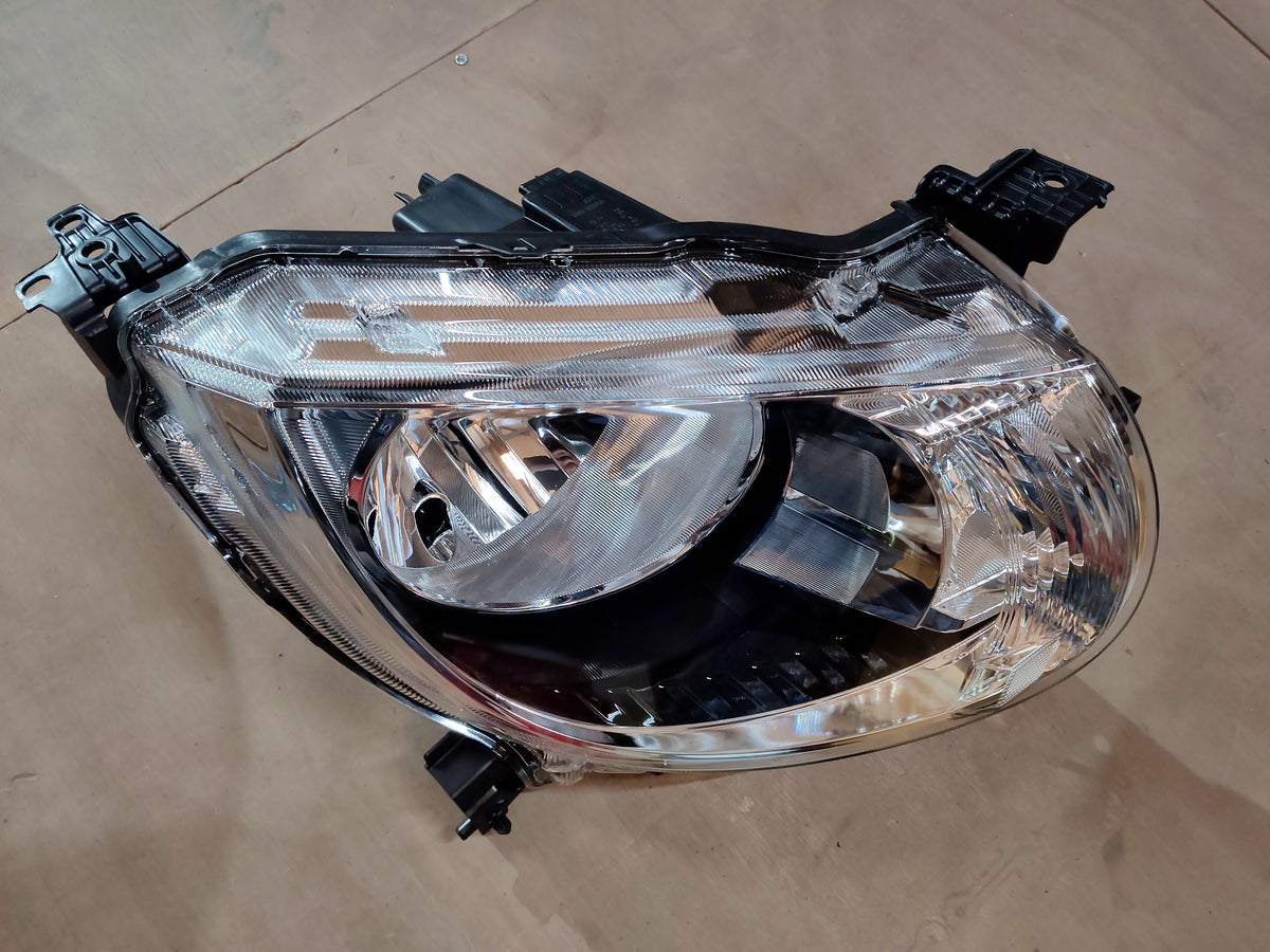 Maruti Suzuki Ignis head lamp assembly in black with clear lens, front view showing the headlight design and mounting points.