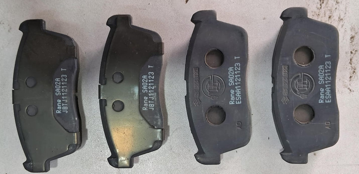 Maruti Suzuki disc brake pad set for vehicle, showing metallic brake pads with brand markings and mounting holes.