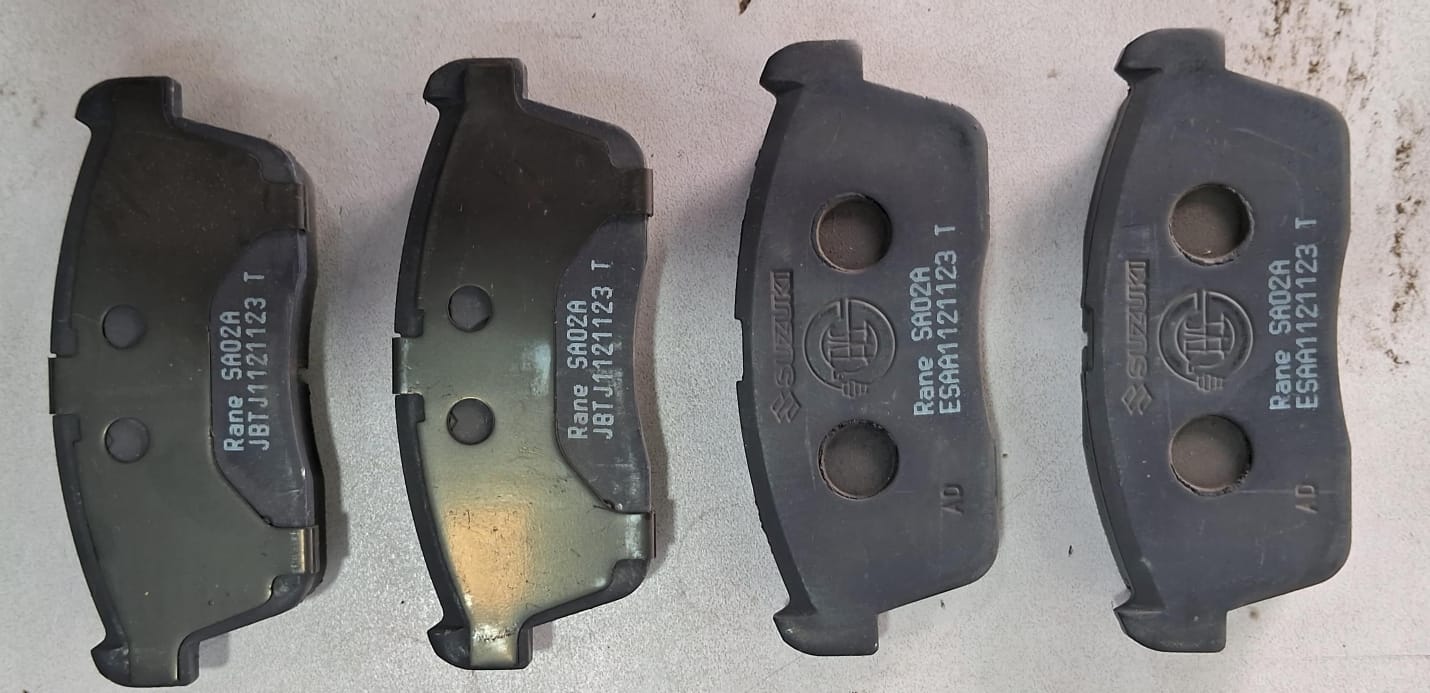 Maruti Suzuki disc brake pad set for vehicle, showing metallic brake pads with brand markings and mounting holes.