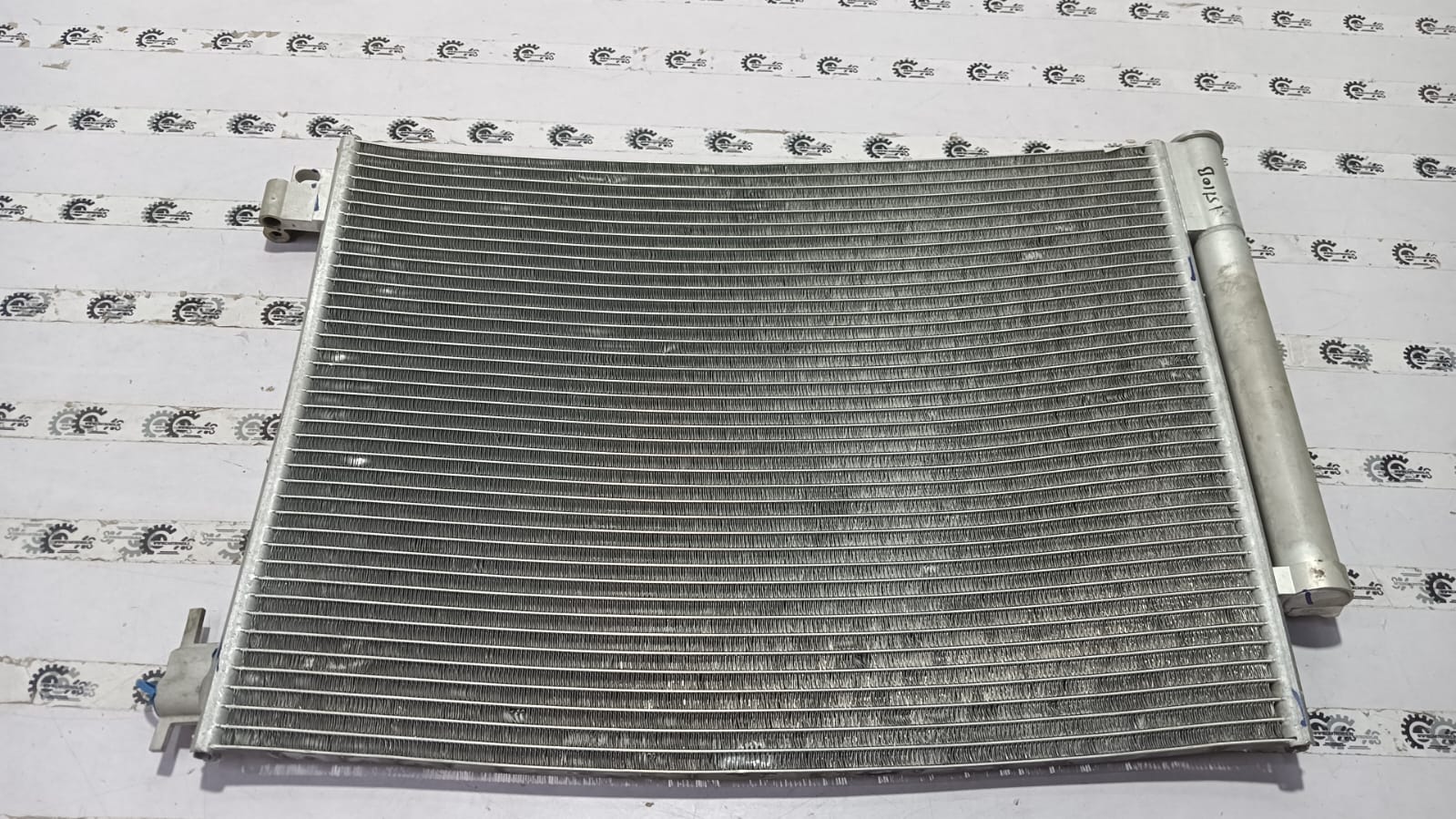 Nissan condenser for Renault Duster vehicle, part number 921006936R, showing the metal radiator component in a car engine bay.