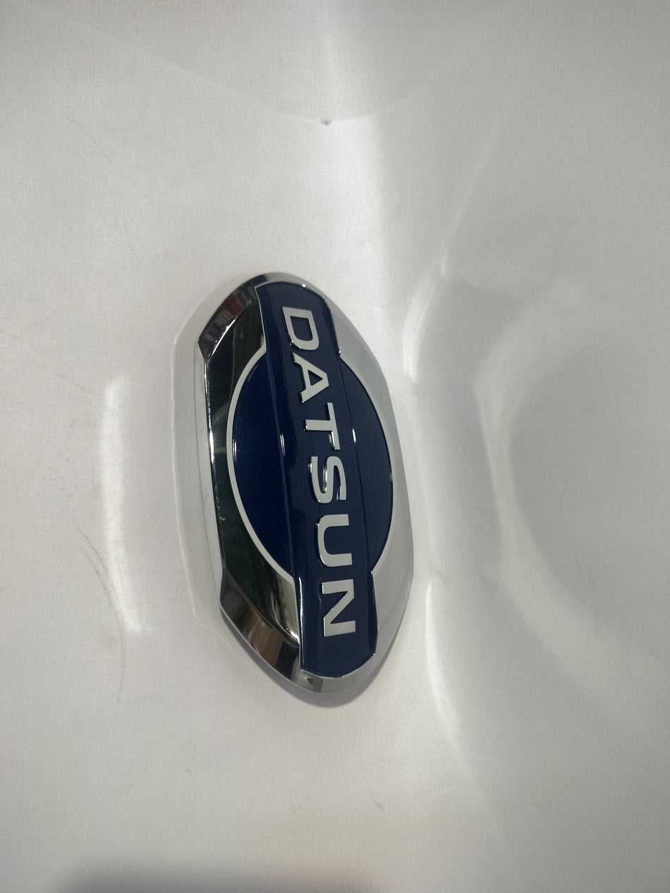 Front view of a Nissan Datsun Go emblem, showing the vehicle's front badge with the Nissan logo on a white background.