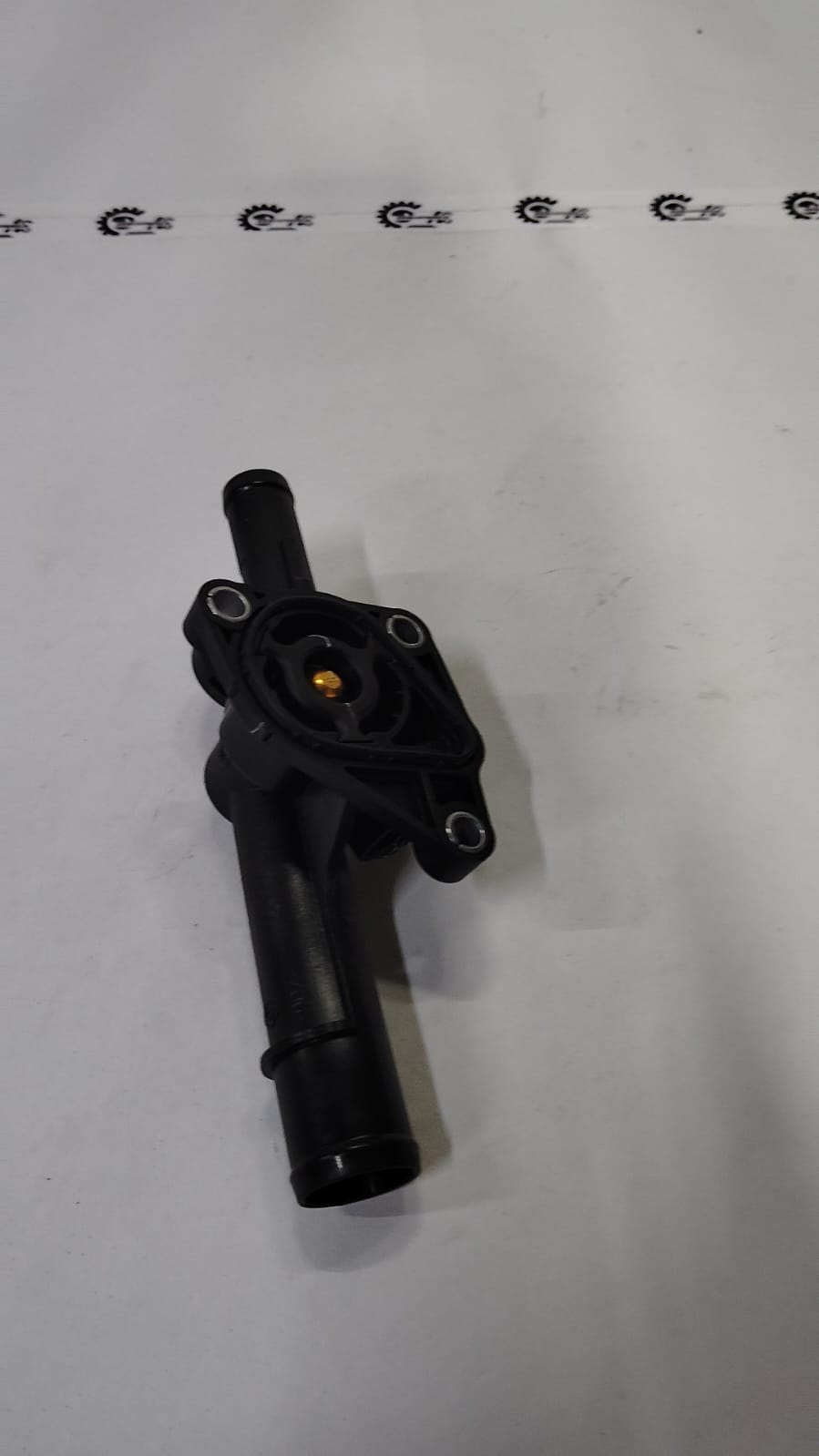 Nissan Kwid thermostat housing part 110600318R, shows the black plastic component with mounting points and connectors.