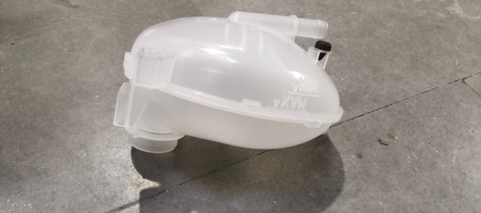 Ford Figo radiator overflow tank assembly, view of the plastic reservoir with connecting hoses and mounting points.