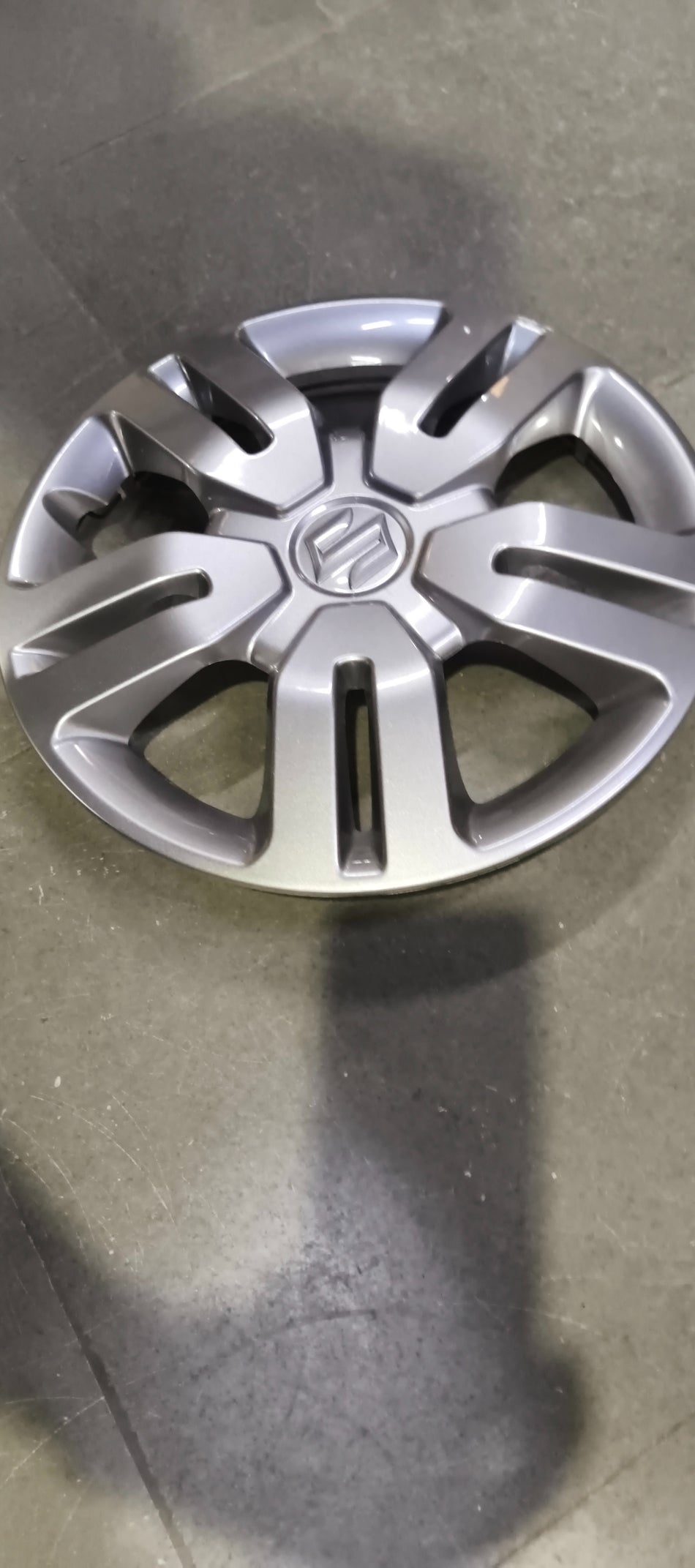 Maruti Suzuki wheel cover 43250M62SA0 installed on car wheel, featuring black and silver design for a stylish look