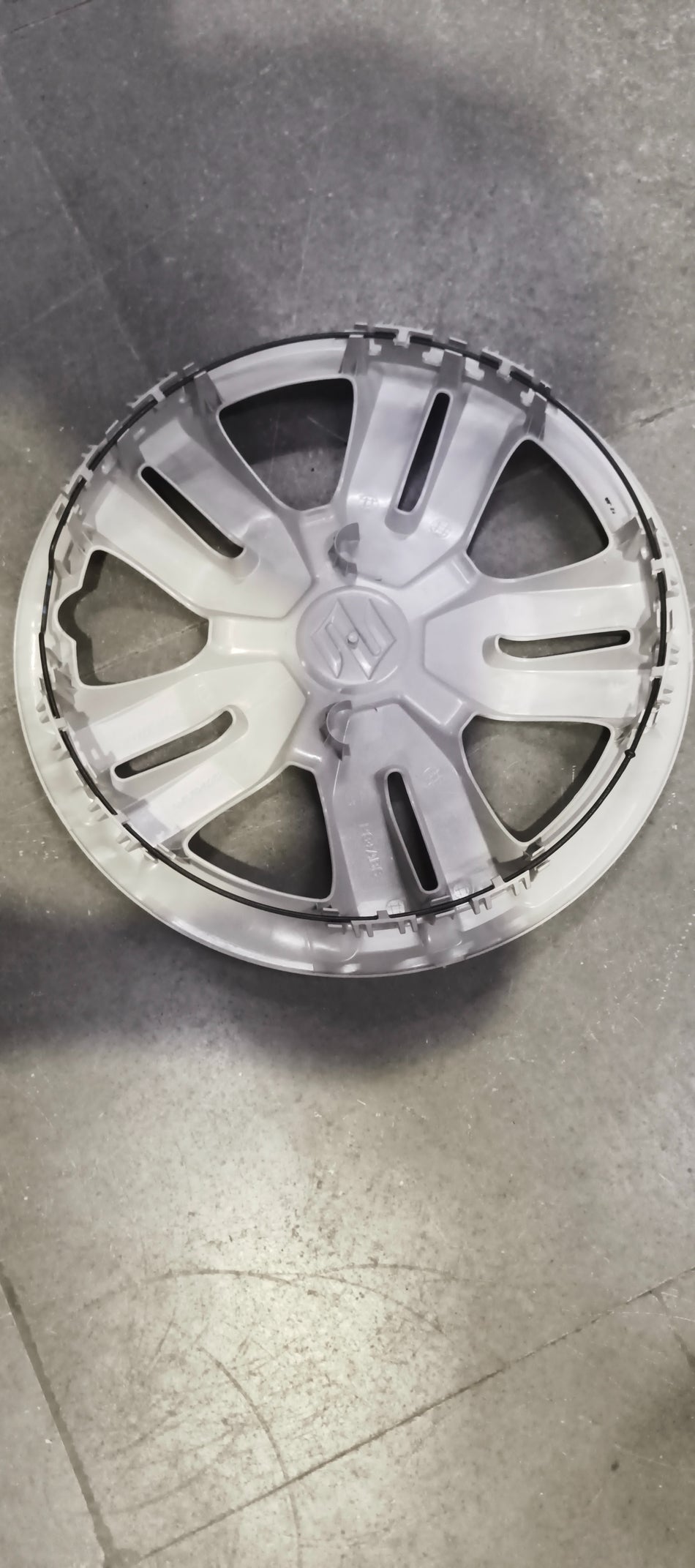 Maruti Suzuki wheel cover model 43250M62SA0 installed on a vehicle, showcasing its stylish design and fit for Maruti Suzuki wheels.