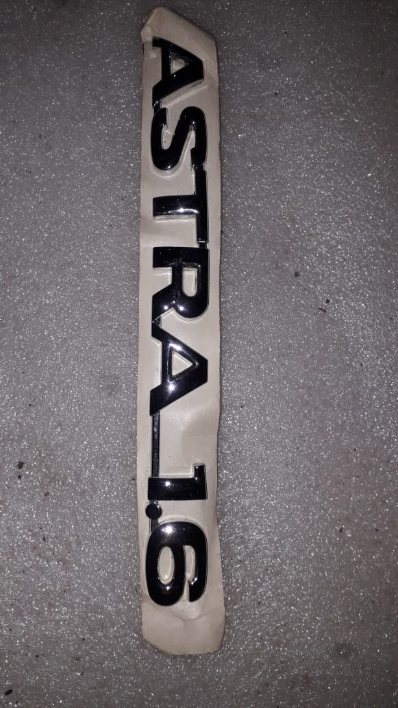CarTrends Astra 1.6 Name Plate for C90556382 spare part, close-up of the vehicle identification badge showing branding and model details.