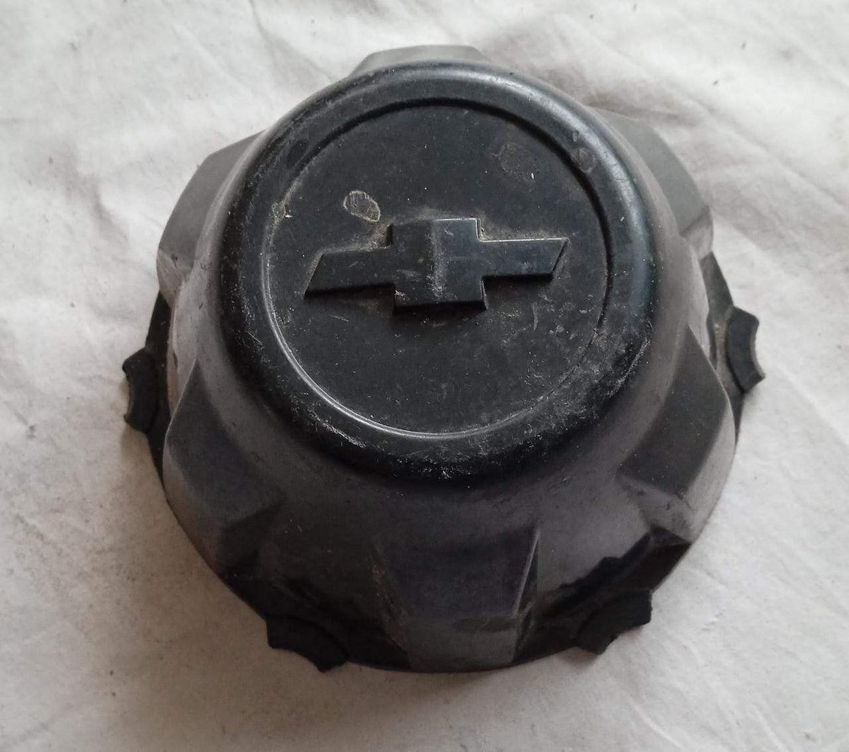 General Motors Tavera wheel cap, black plastic cover with GM logo, designed for Tavera vehicle wheel aesthetic and protection.
