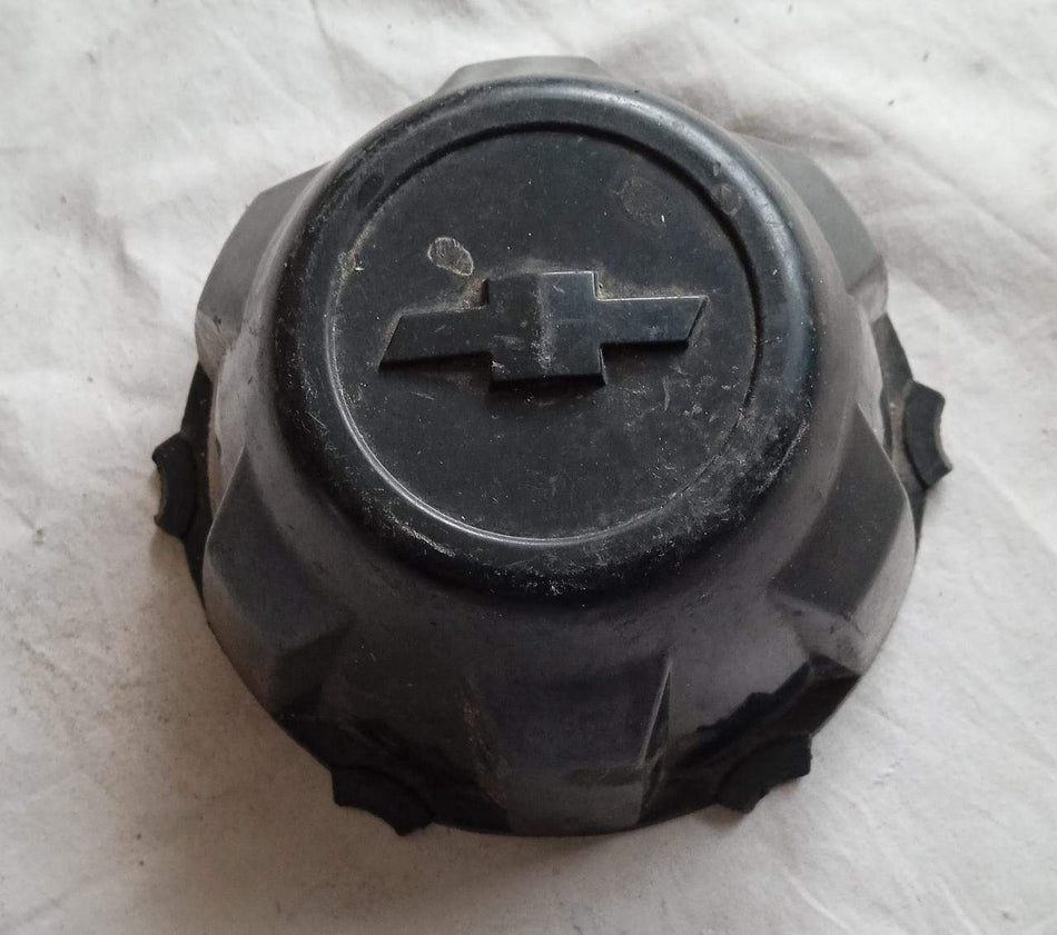 General Motors Tavera wheel cap featuring the GM logo, designed for Tavera vehicle wheels, black plastic finish with branding details.