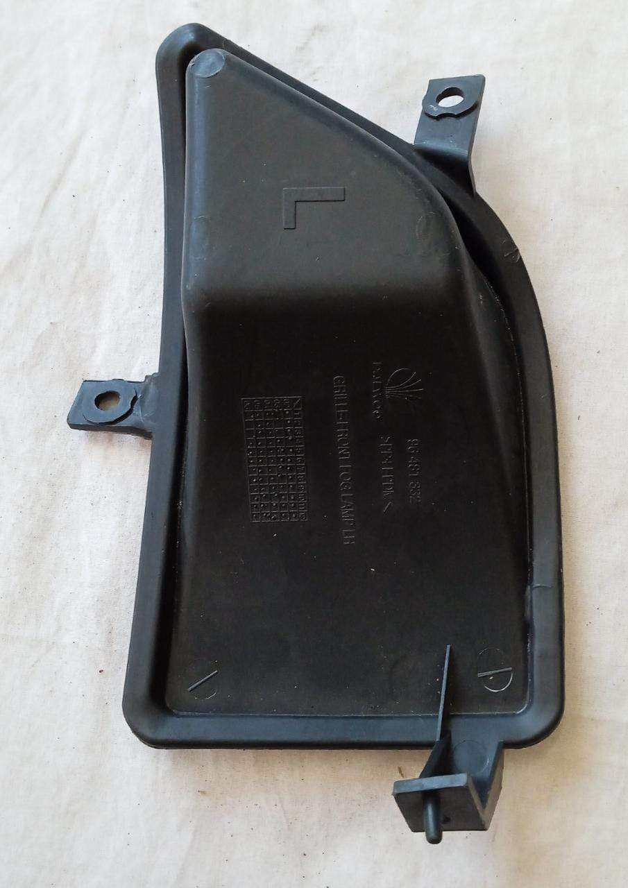 General Motors fog lamp cover for left side of Chevrolet Aveo, model J96481332, in black plastic with textured surface.