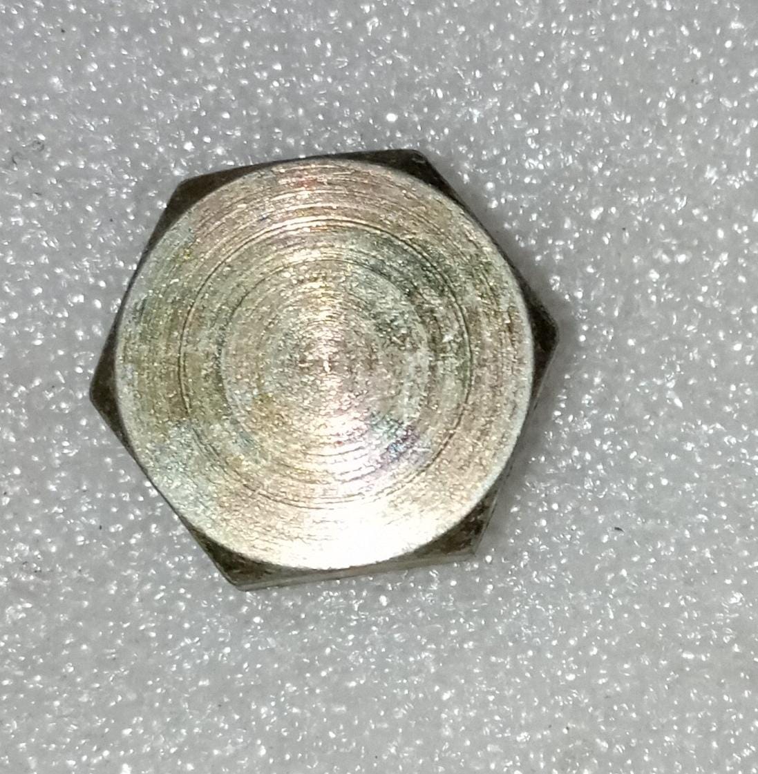 General Motors Tavera plug drain axle case, automotive part for vehicle maintenance, showing the black plastic drain plug on the axle.