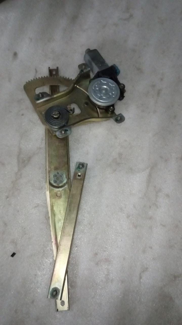 General Motors front window regulator for Aveo J981542L0, showing the mechanical assembly with cables and mounting points.