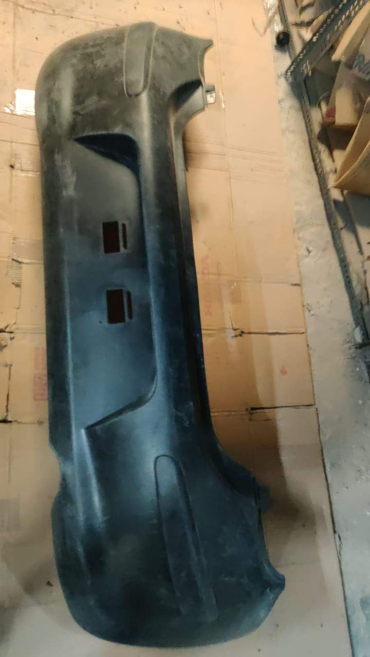 Nissan rear bumper model 850221HB0H, car part image showing the black plastic bumper with mounting points and detailing.